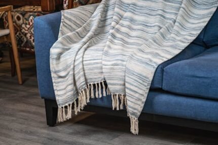 A comfortable blue sofa draped with a striped throw blanket, perfect for home interiors.